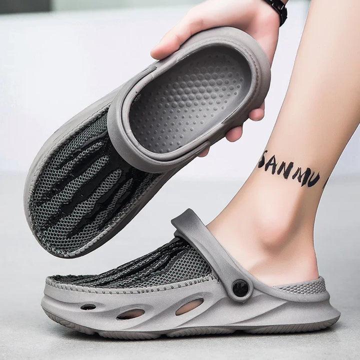 grey and black breathable mesh clogs with adjustable heel strap worn on foot against white background