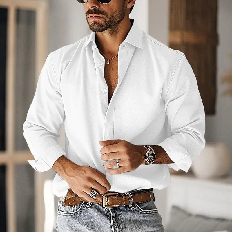 stylish man wearing white button-up shirt, brown belt, blue jeans, silver watch, rings, and sunglasses