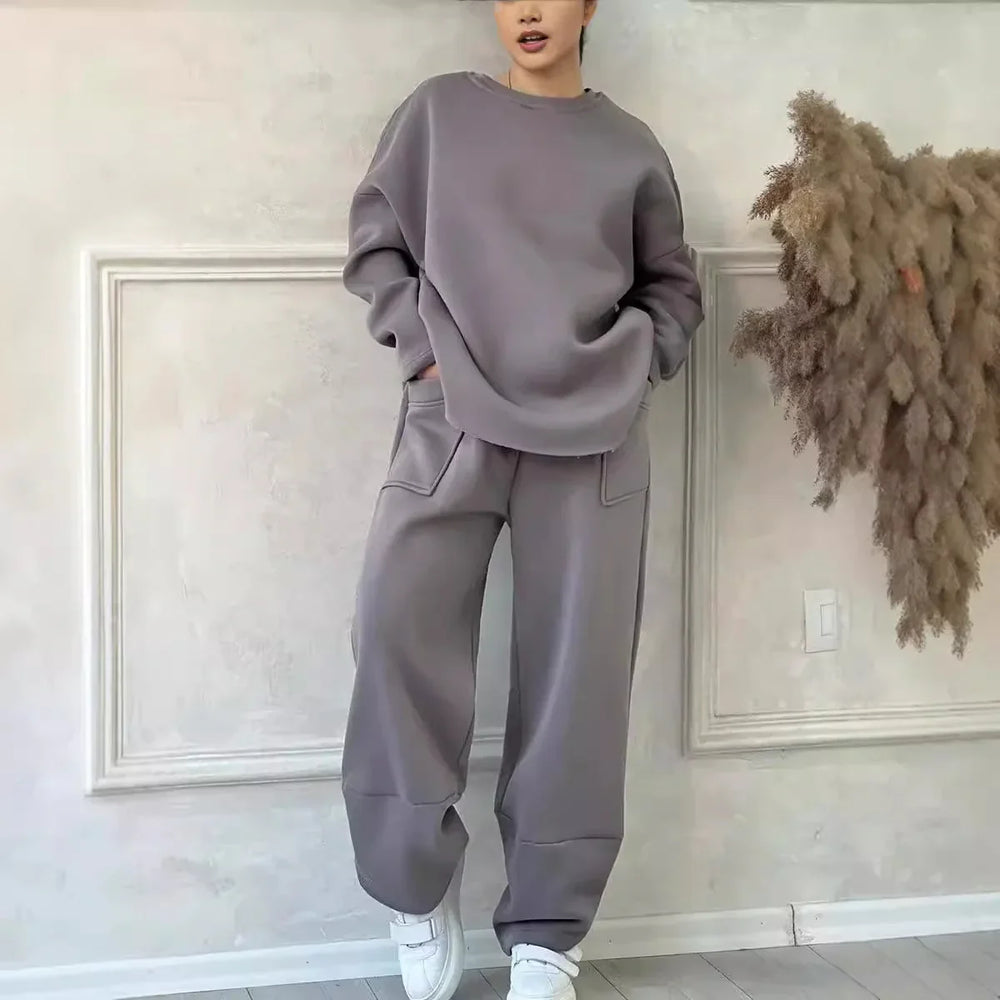 Woman wearing gray oversized sweatshirt and matching wide leg pants with pockets in minimalist room