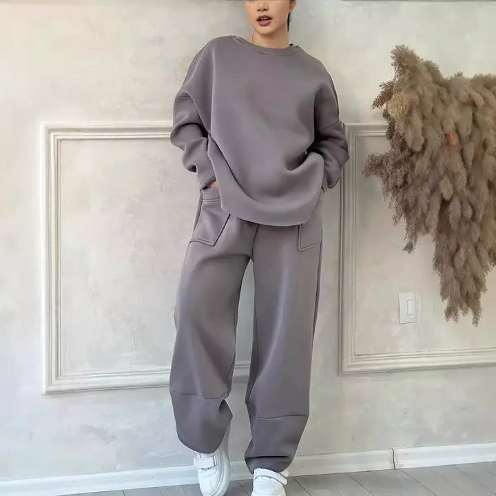 Woman wearing gray oversized sweatshirt and matching wide leg pants with pockets in minimalist room