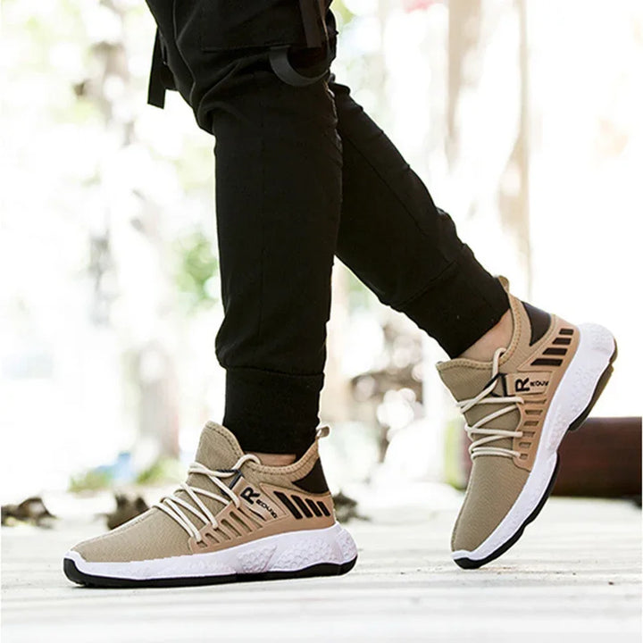 Men's beige and black running shoes with white laces worn with black pants outdoors