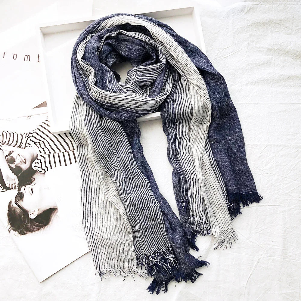 Blue and white striped lightweight scarf with fringed edges on a white fabric background