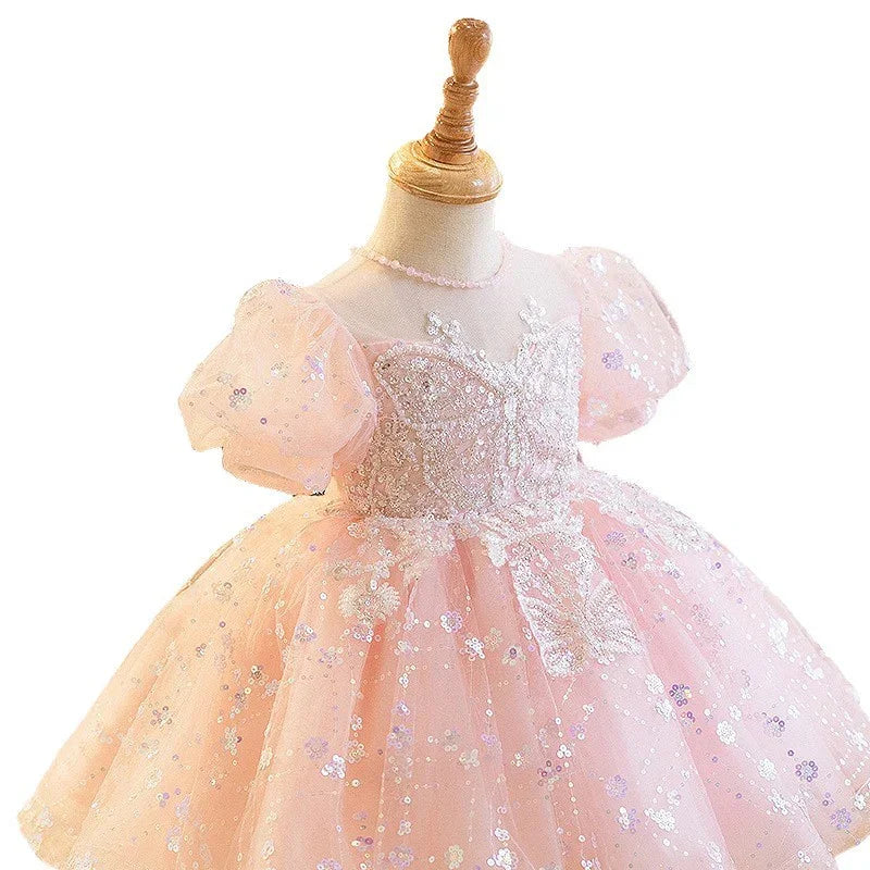 Pink toddler dress with puff sleeves and sequin butterfly details on a mannequin