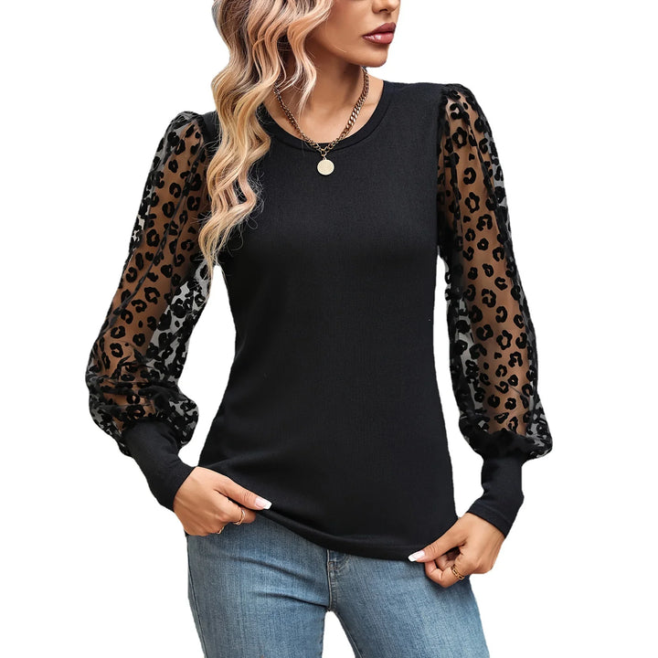 Woman wearing black top with sheer leopard print puff sleeves and blue jeans