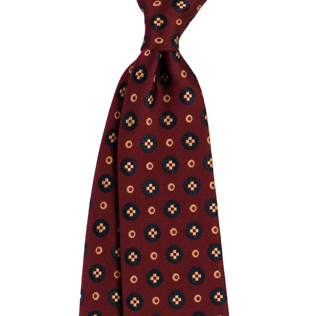 Burgundy tie with blue and gold geometric circular pattern on white background