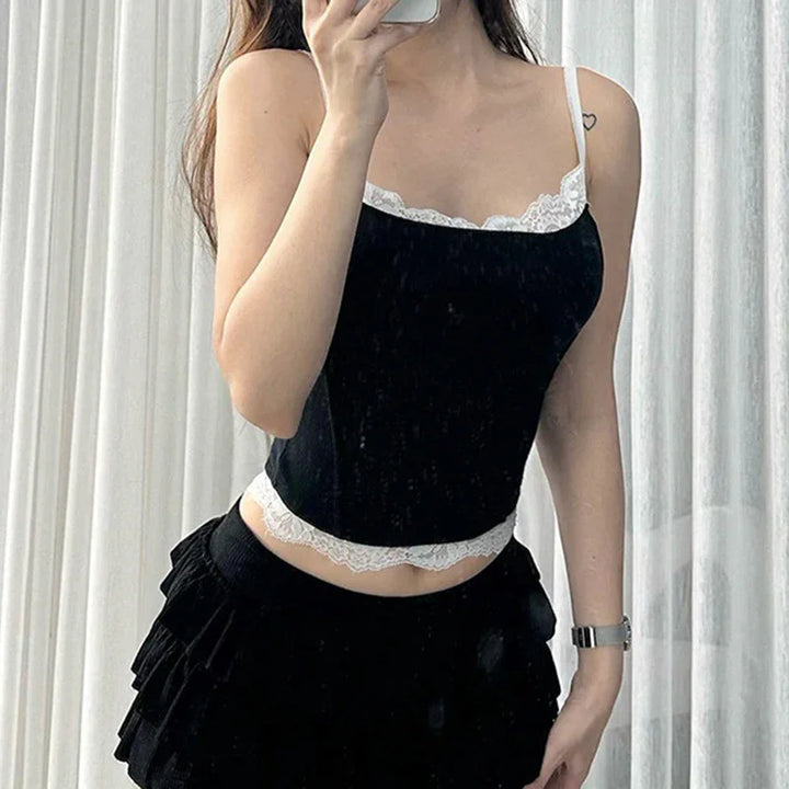Woman wearing black lace-trimmed camisole and tiered black skirt taking mirror selfie