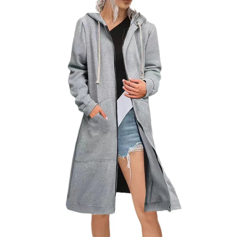 Woman wearing long grey zip-up hoodie with pockets and drawstring hood over black top and denim shorts
