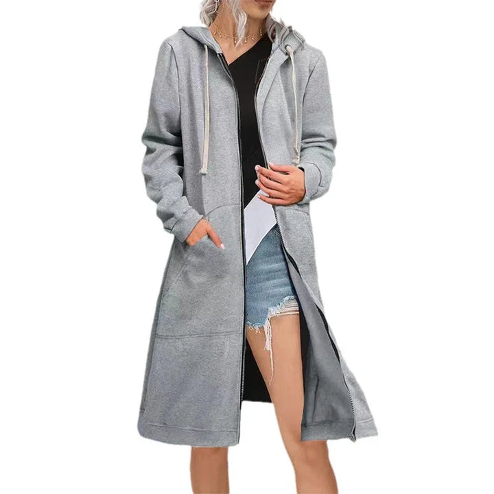 Woman wearing long grey zip-up hoodie with pockets and drawstring hood over black top and denim shorts
