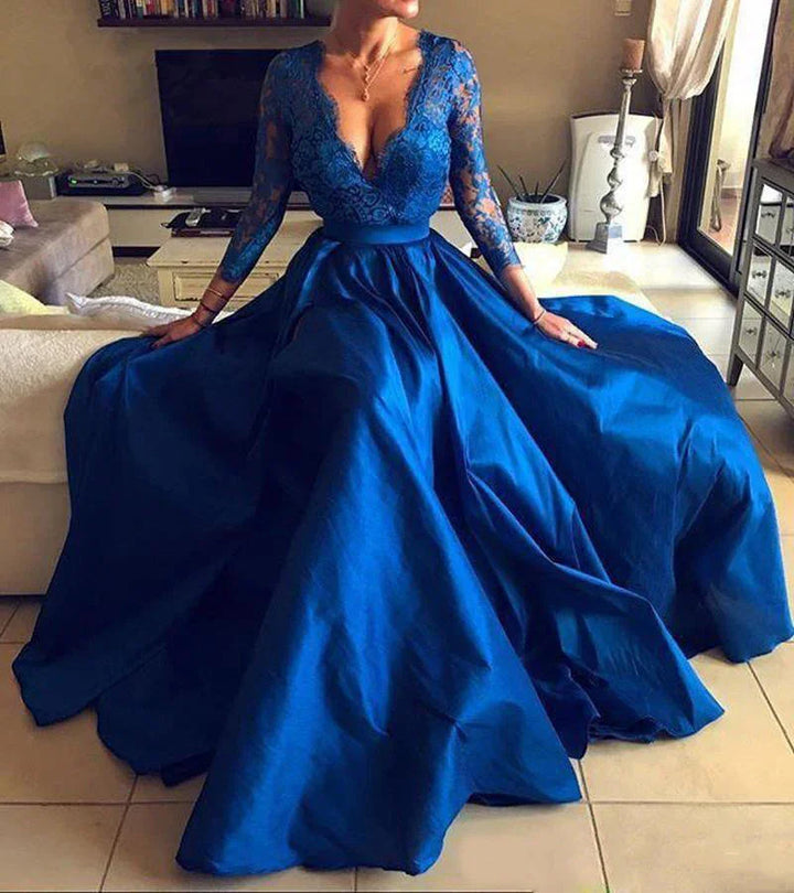 Woman wearing elegant royal blue evening gown with lace sleeves and deep V-neck sitting indoors