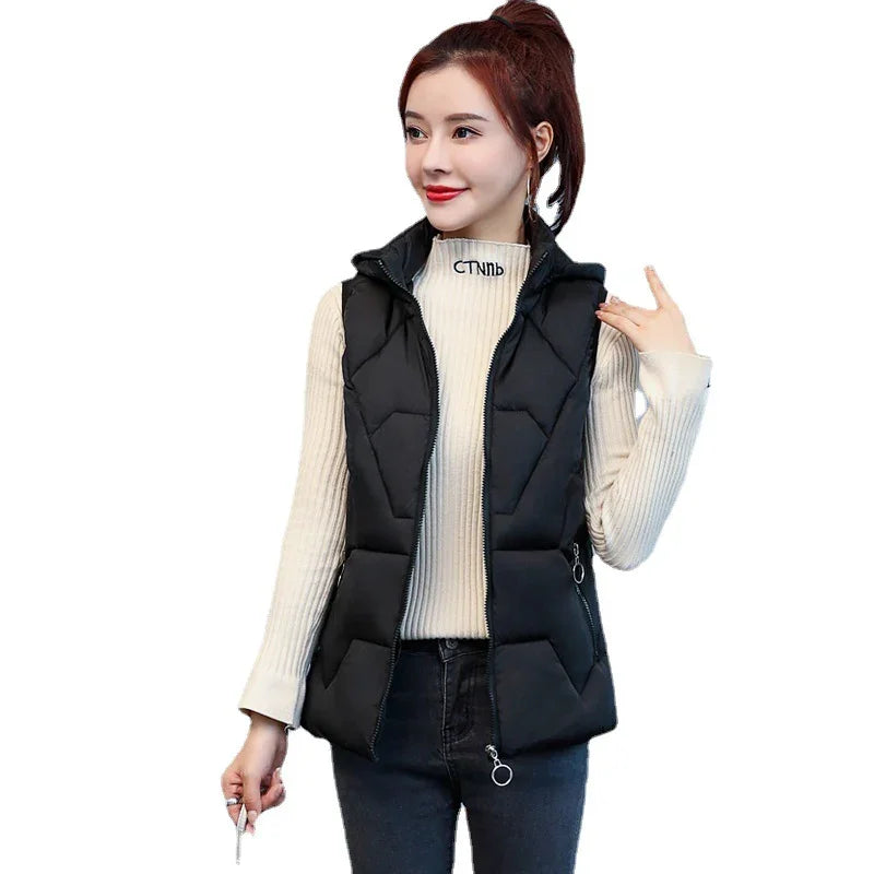 Woman wearing black padded sleeveless vest over cream ribbed turtleneck sweater and dark jeans