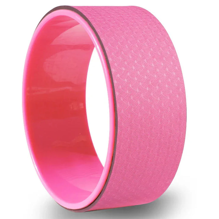 Pink yoga wheel with textured surface on white background