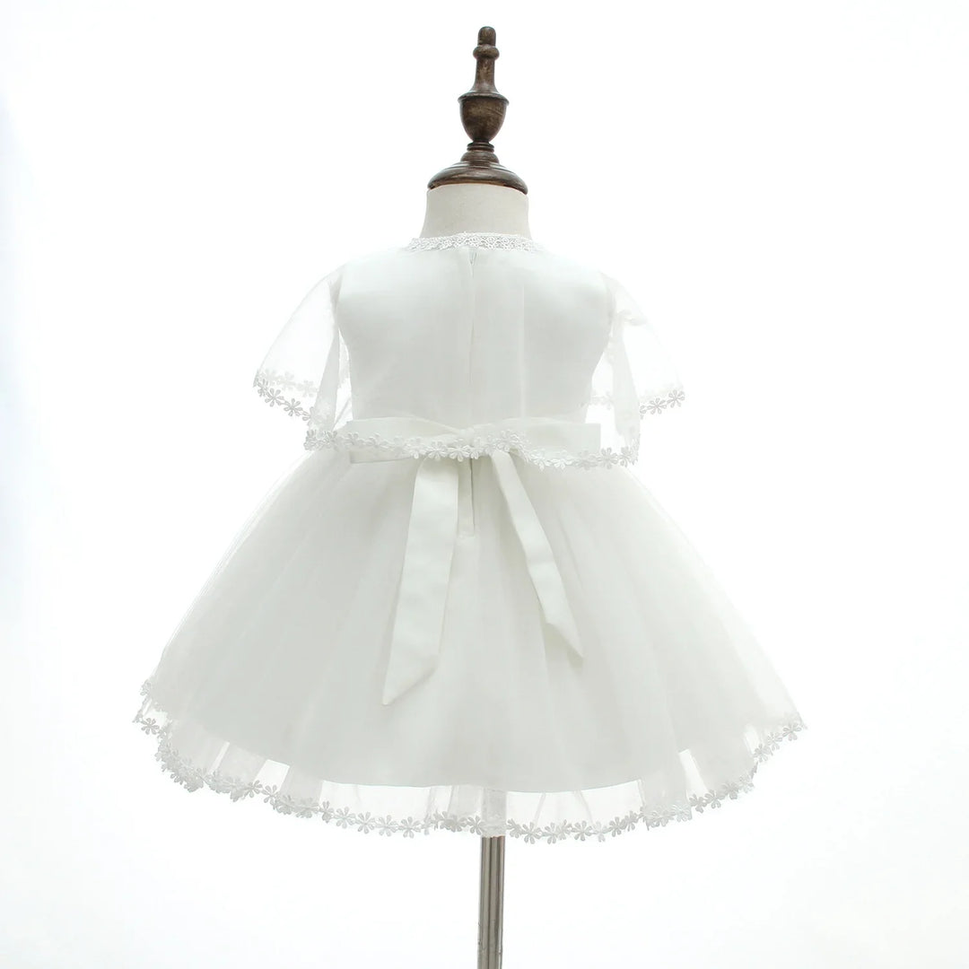 Back view of white baby dress with sheer floral lace sleeves and hem on dress form