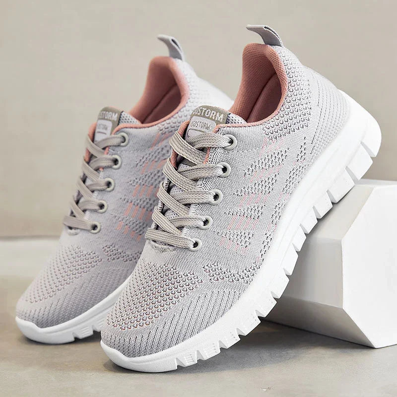 Light gray and pink knit athletic sneakers with white thick sole on gray and white background