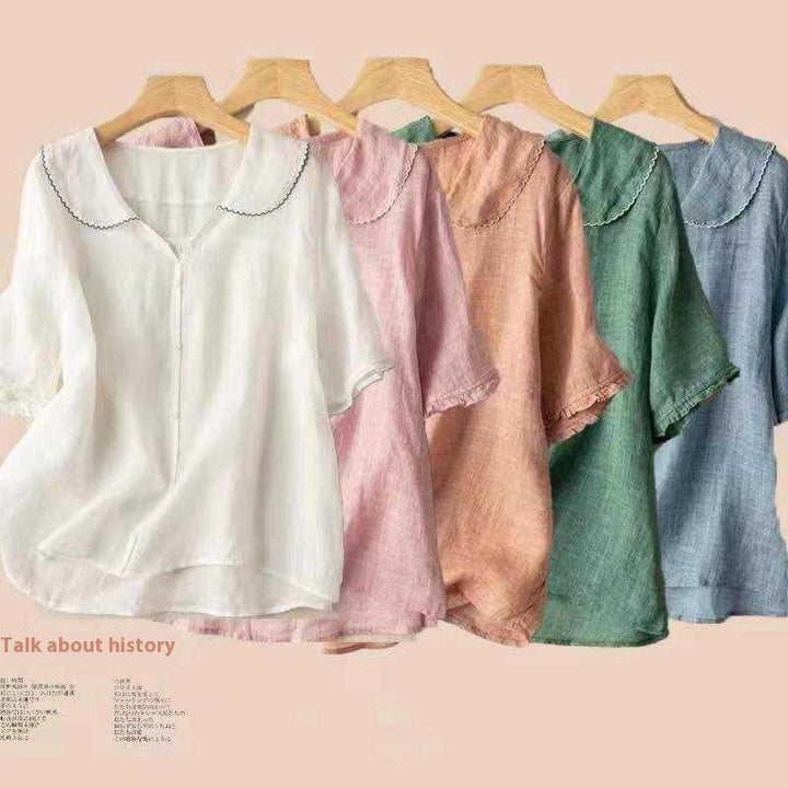 Five lightweight linen blouses in white, pink, peach, green, and blue with scalloped collars on wooden hangers