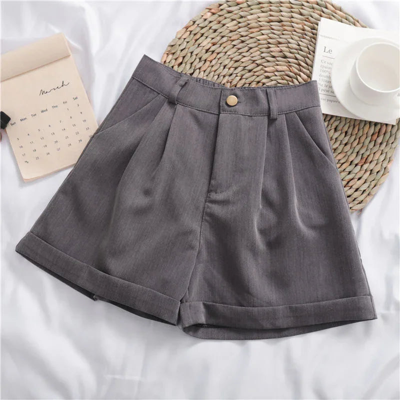 Gray high-waisted pleated shorts with button and belt loops on white fabric with calendar and cup