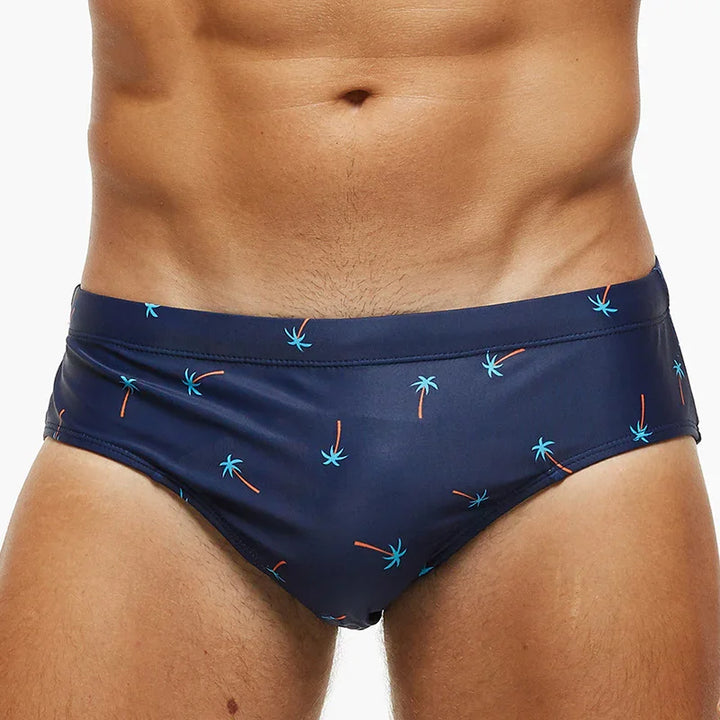 Close-up of man wearing navy blue swim briefs with small palm tree print
