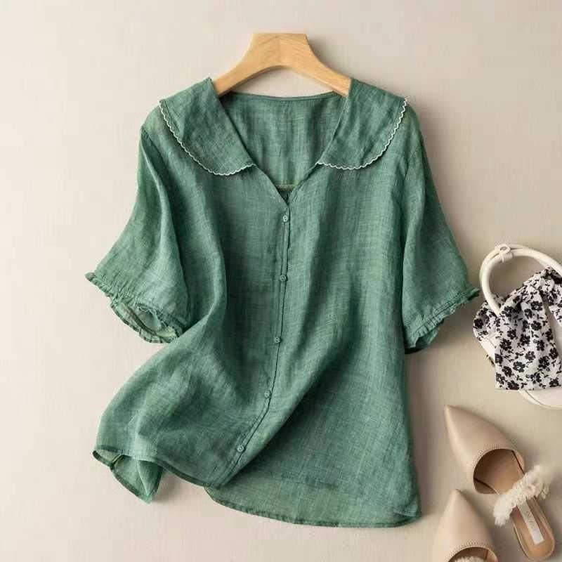 Green linen button-up blouse with scalloped collar and ruffled short sleeves on wooden hanger