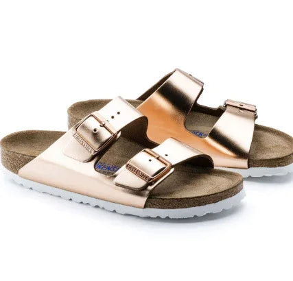 Metallic rose gold double-strap Birkenstock sandals with buckle closures and white soles