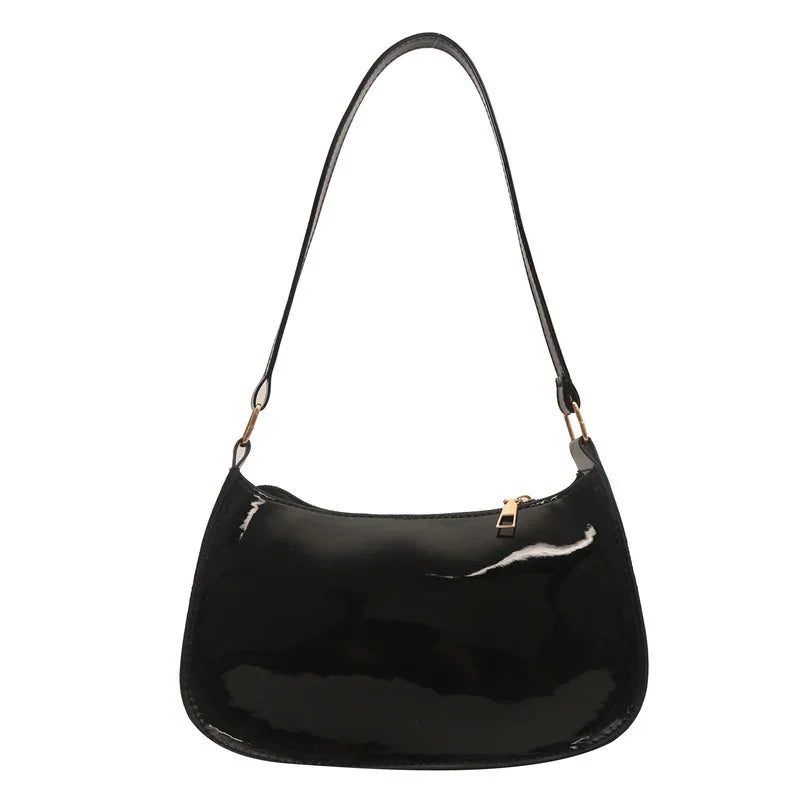 Black patent leather shoulder bag with gold zipper and slim strap on white background