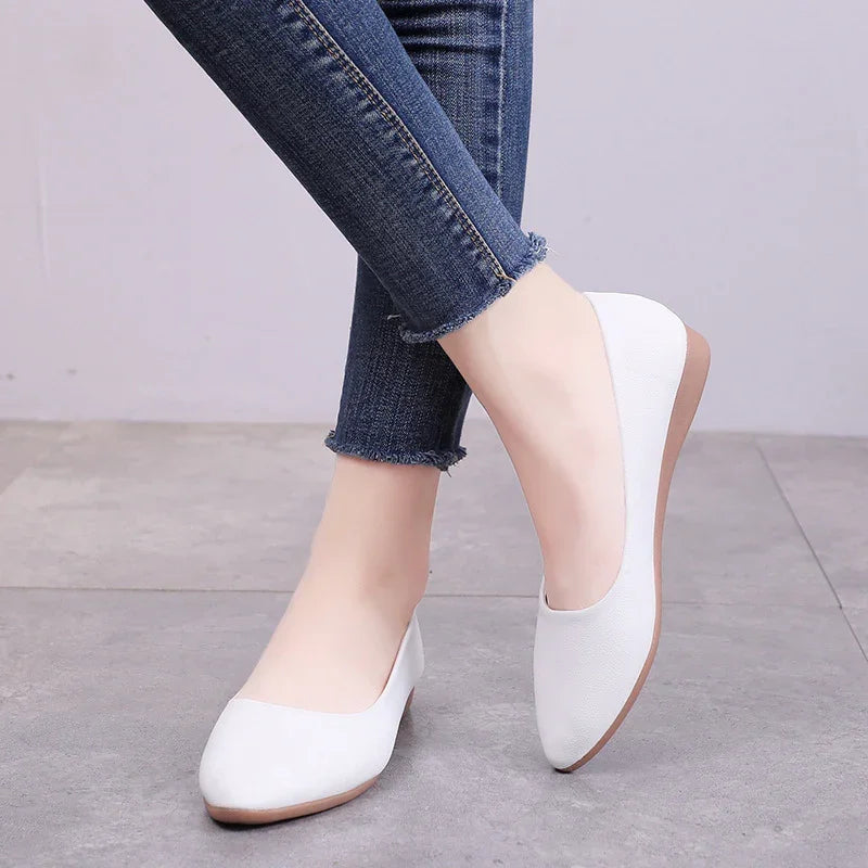 Woman wearing white flat ballet shoes with pointed toes and blue frayed hem skinny jeans