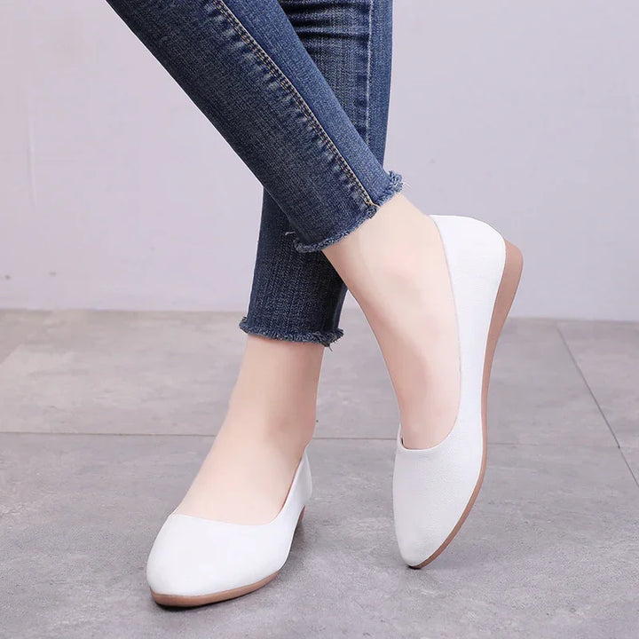Woman wearing white flat ballet shoes with pointed toes and blue frayed hem skinny jeans