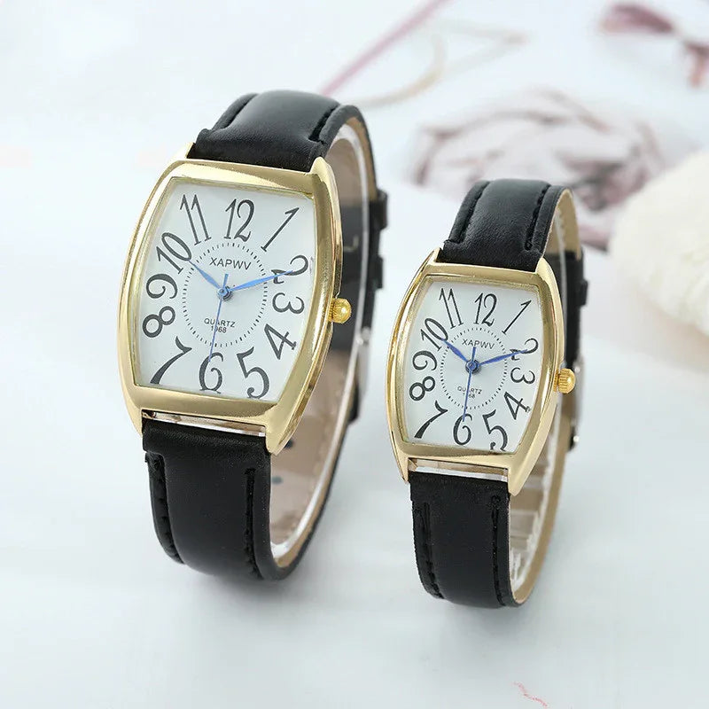 Pair of gold-tone wristwatches with black leather straps and white dials featuring bold numerals
