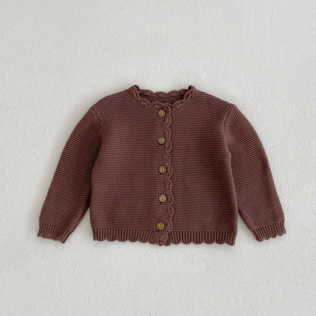 Brown knitted baby cardigan with wooden buttons and scalloped edges laid flat on white background