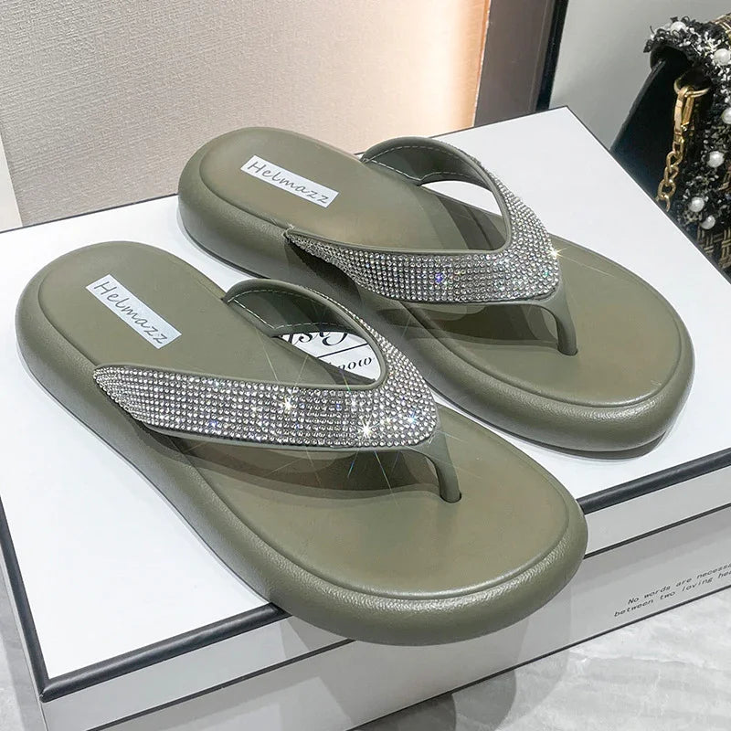 Olive green flip-flops with glittering rhinestone straps on a white box, brand Helmazz