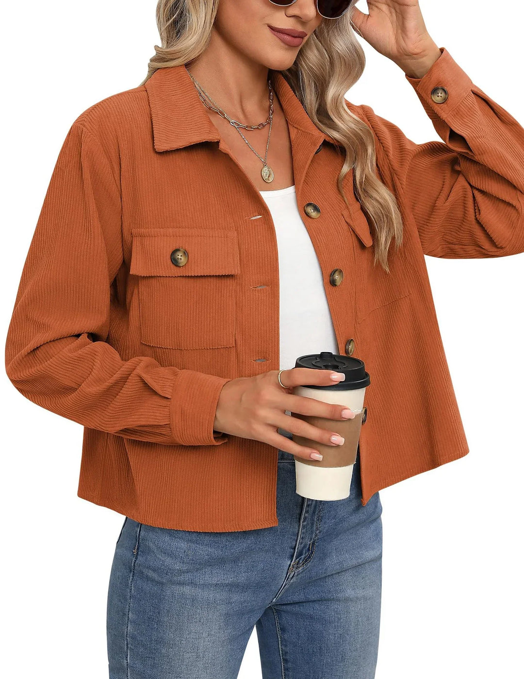 Woman wearing rust-colored corduroy jacket with button pockets holding a coffee cup