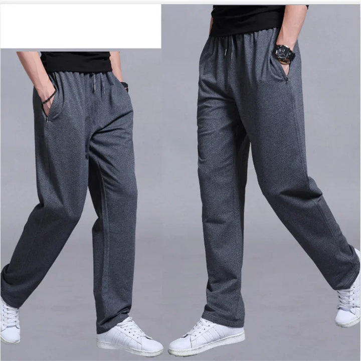 Men's dark gray casual sweatpants with elastic waistband and side pockets, worn with white sneakers