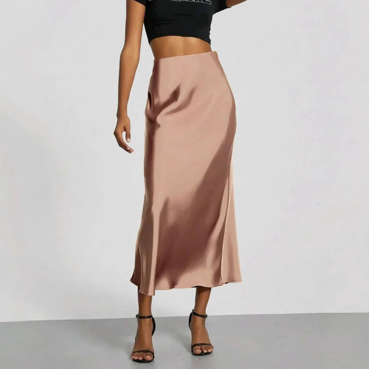 Woman wearing shiny beige satin midi skirt with black cropped top and black high-heeled sandals