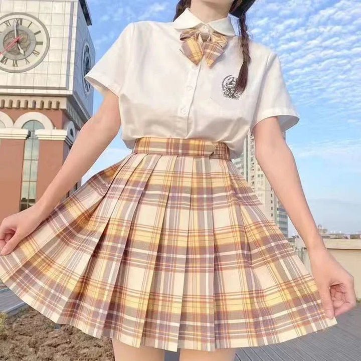 Girl wearing white shirt with emblem and plaid bow, yellow and brown pleated skirt, clock tower background