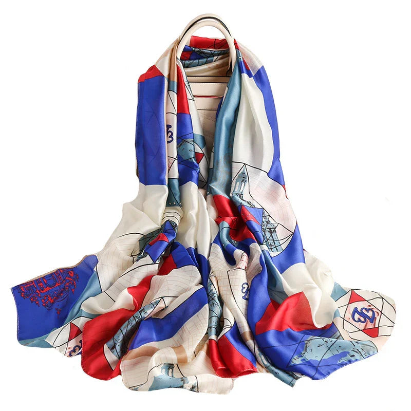 Colorful silk scarf with red, blue, cream geometric and architectural patterns draped over a leather handbag