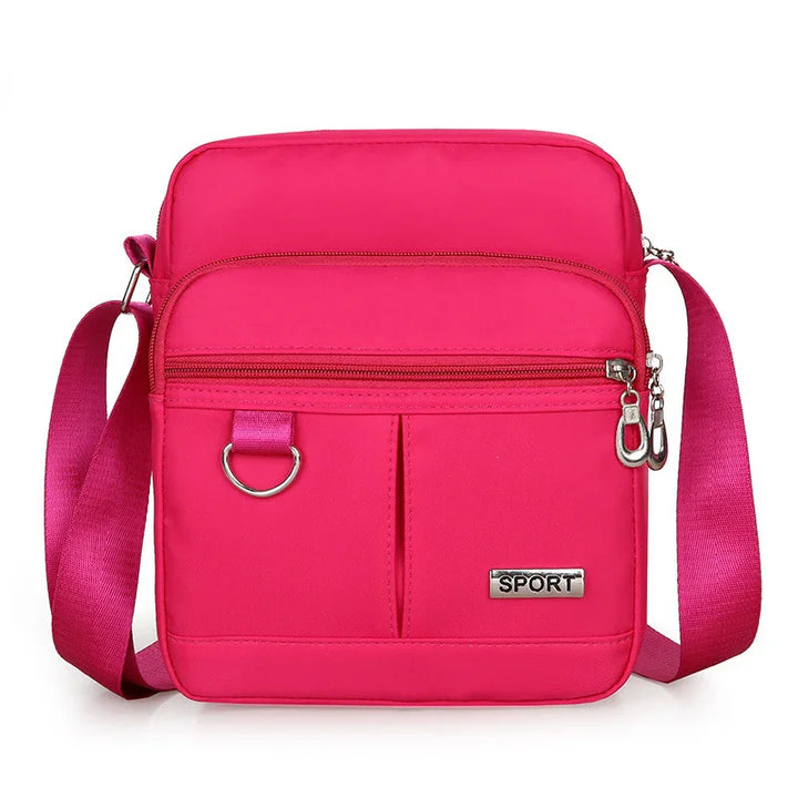 Bright pink sport crossbody bag with adjustable strap, front zipper pocket, and metal detail