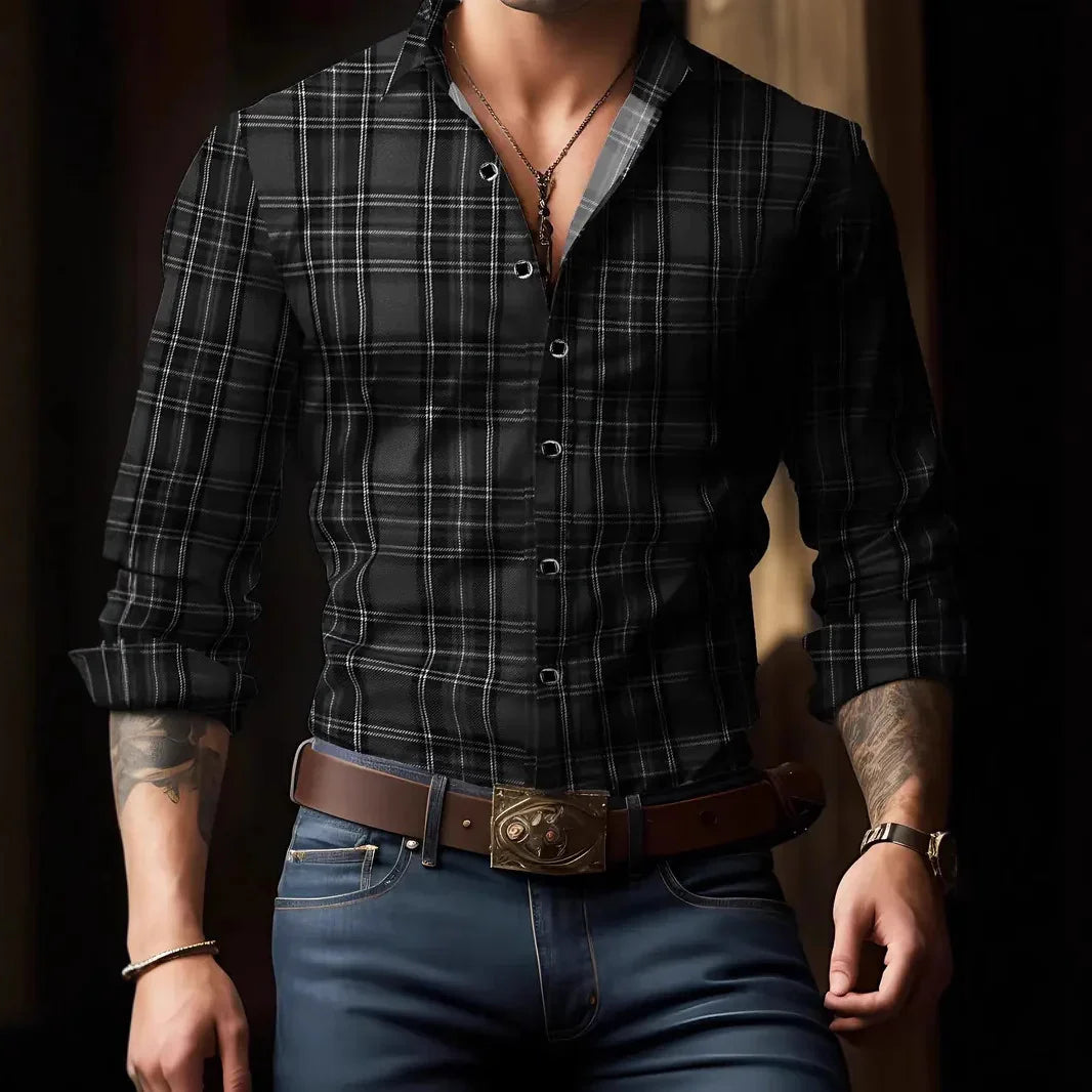 Man wearing black plaid button-up shirt with rolled sleeves, brown belt, blue jeans, and accessories