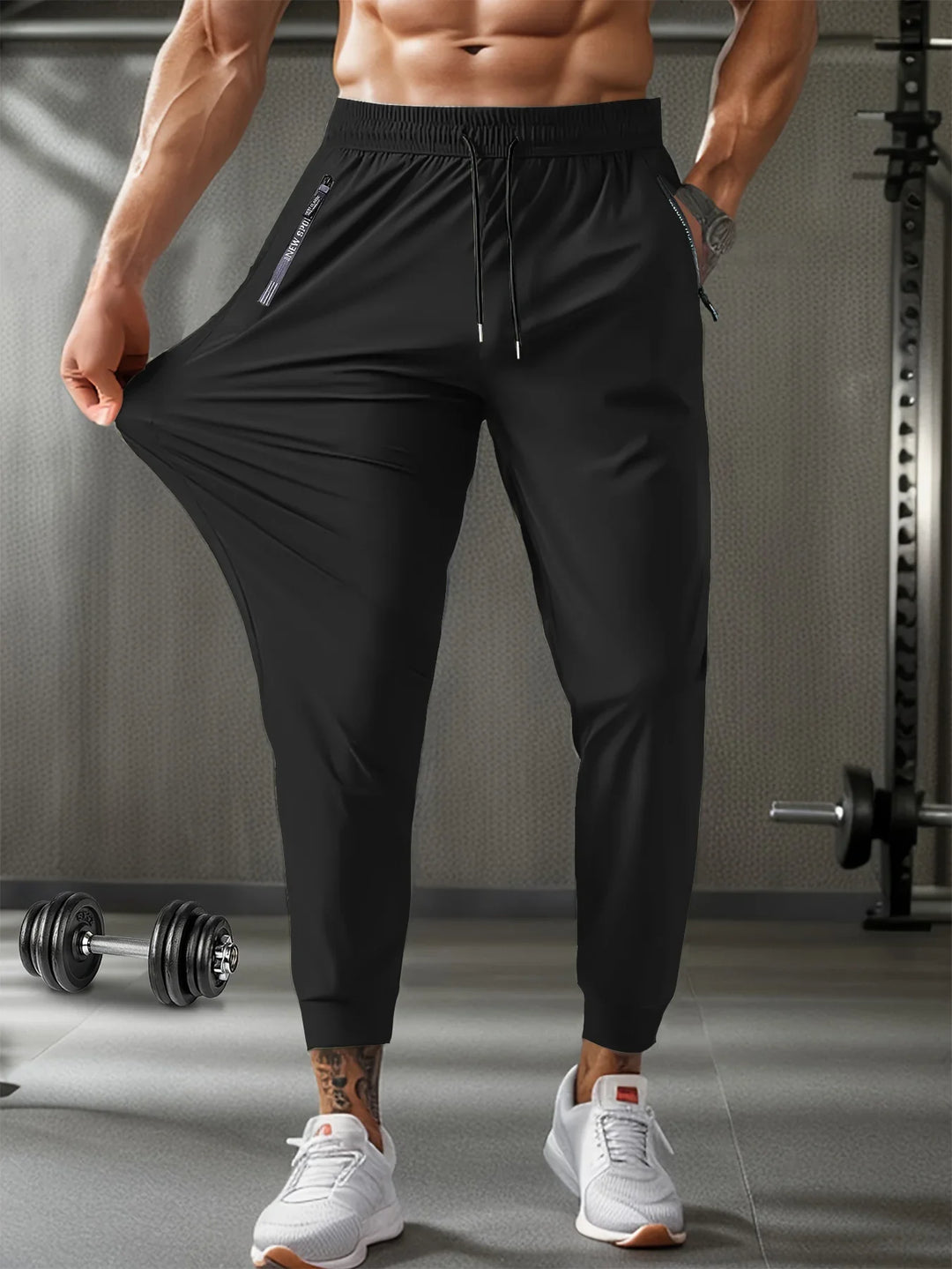 Muscular man wearing stretchy black jogger pants and white sneakers in gym setting