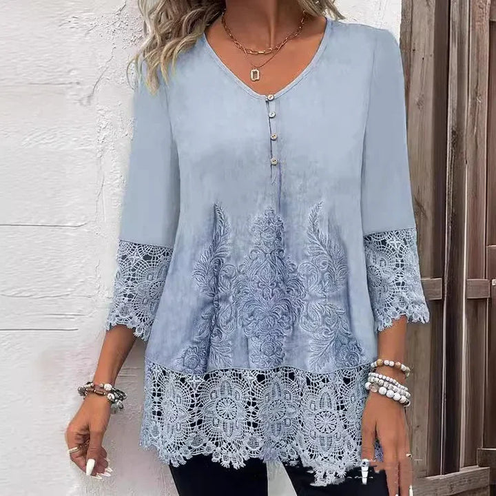 Light blue women's blouse with lace sleeves and hem, embroidered front, and three buttons at neckline