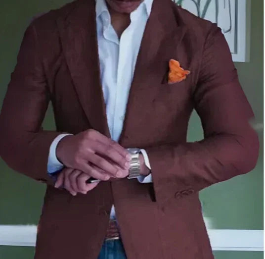 Man wearing brown blazer with orange pocket square and white shirt, adjusting silver wristwatch
