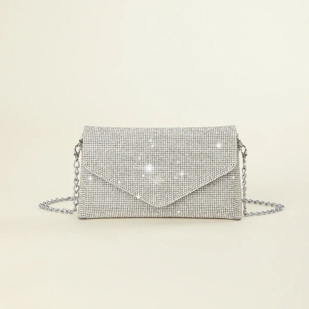 Silver rhinestone envelope clutch bag with chain strap on beige background