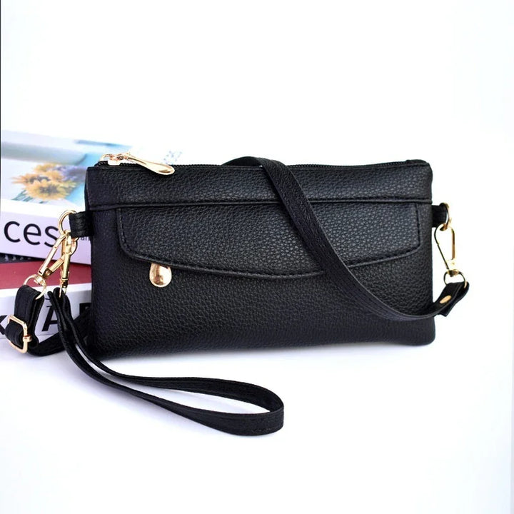 Black textured leather crossbody purse with gold hardware and detachable wrist strap
