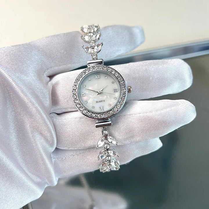Elegant silver women's quartz wristwatch with crystal-studded bezel and decorative bracelet held by gloved hand