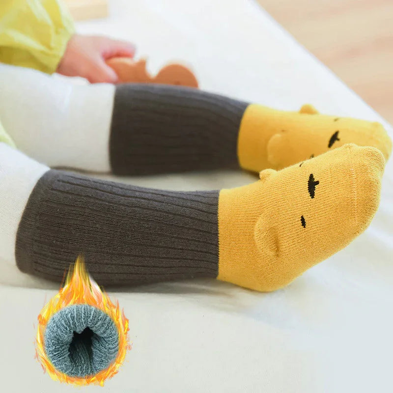 Child wearing cozy yellow and gray ribbed knit warm socks with cute bear face design