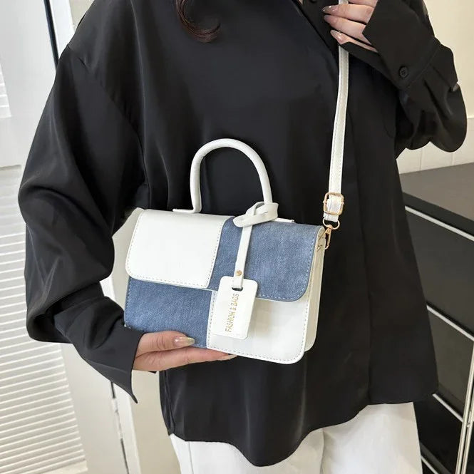 Woman holding stylish white and denim patchwork crossbody bag with top handle and adjustable strap