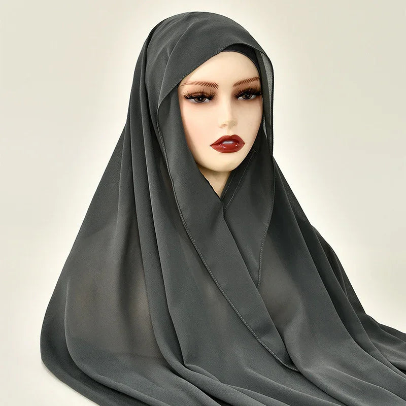 Mannequin wearing black hijab with dramatic eyelashes and dark red lipstick on plain background