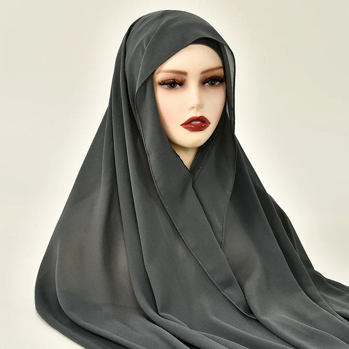 Mannequin wearing black hijab with dramatic eyelashes and dark red lipstick on plain background
