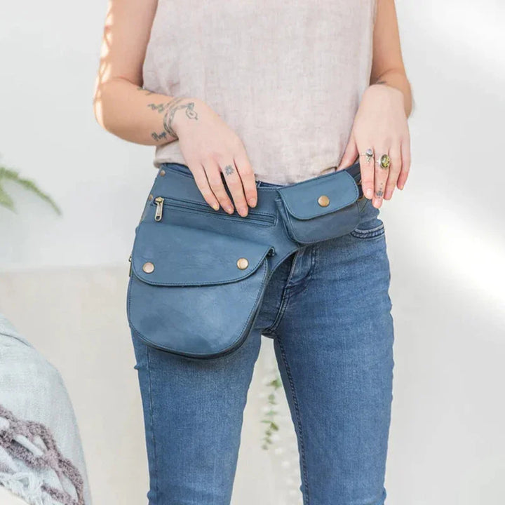 Woman wearing blue leather hip bag with multiple pockets and gold buttons over jeans