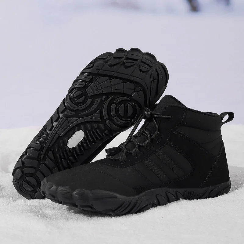 Pair of black high-top hiking shoes with rugged soles on snow background