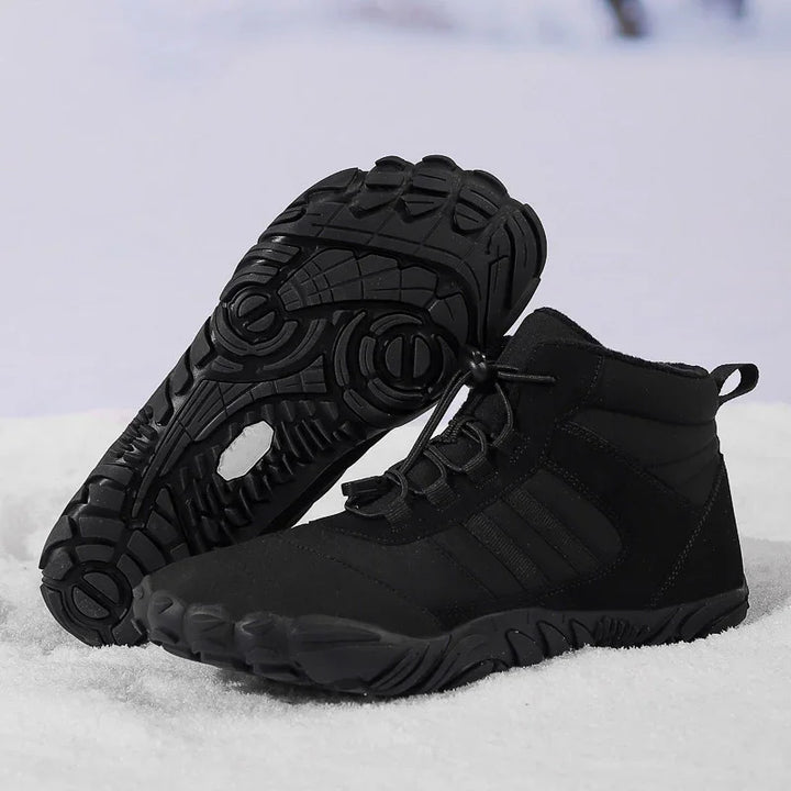 Pair of black high-top hiking shoes with rugged soles on snow background