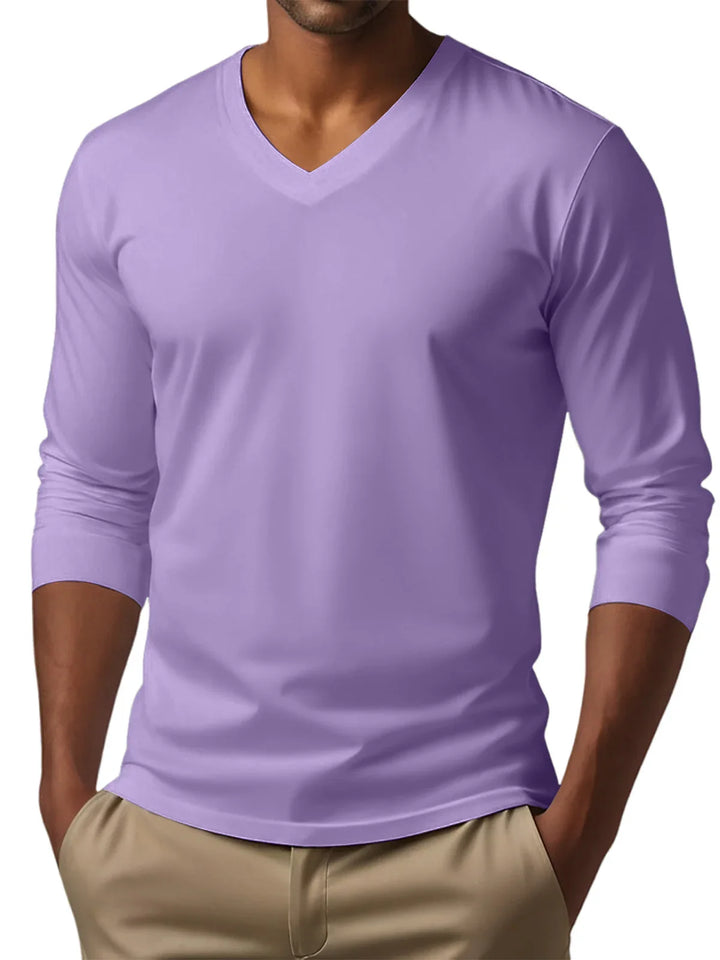 Man wearing a light purple long sleeve V-neck shirt with beige pants, hands in pockets
