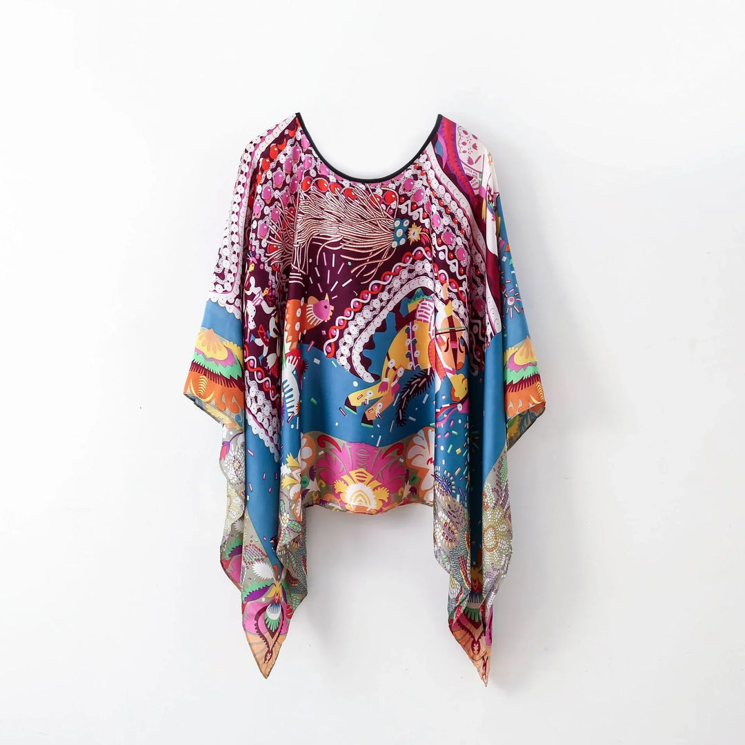 Colorful bohemian loose blouse with abstract and floral patterns, hanging on white background
